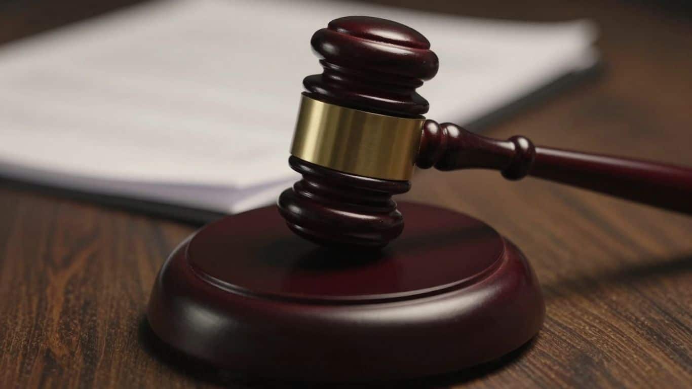 Gavel hitting a block, legal documents in background.